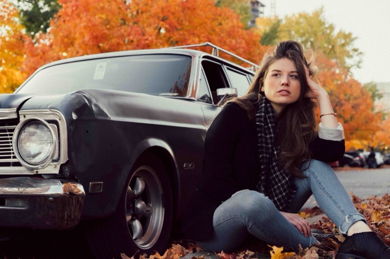 Senior portrait by a vintage car in autumn leaves